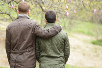 Gay couple hugging and walking in park